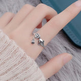 Bague Poisson Couleur Argent Ajustable, portée sur un doigt, montrant son motif de poisson et son charme pendeloque.