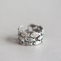 Bague Poissons Triple Ajustable en argent, formée de plusieurs poissons ajourés qui créent un anneau large et ajustable.