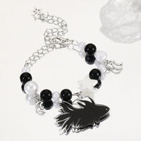 Gros plan sur le Bracelet Poisson Betta Noir avec Perles et Étoiles, mettant en valeur le pendentif poisson noir et le contraste des perles.