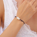 Bracelet Poisson Blanc Nacré Ajustable, illustrant la brillance du pendentif sur un cordon noir