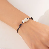 Bracelet Poisson Blanc Nacré Ajustable, porté au poignet, mettant en valeur le pendentif discret en céramique.