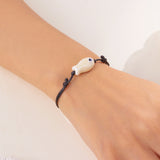 Bracelet Poisson Blanc Nacré Ajustable, porté au poignet, mettant en valeur le pendentif discret en céramique.