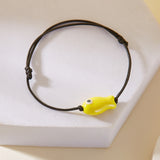 Gros plan sur le Bracelet Poisson Jaune Ajustable, posé sur un support, montrant le poisson en céramique.