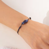 Gros plan sur le Bracelet Poisson Noir Ajustable, soulignant la finition brillante du pendentif poisson.
