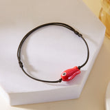 Bracelet Poisson Rouge Ajustable, posé sur un support, mettant en évidence le pendentif en céramique.