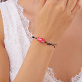Bracelet Poisson Rouge Ajustable porté au poignet, soulignant la teinte éclatante du poisson sur un cordon noir.