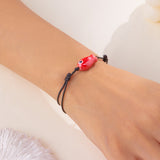 Gros plan sur le Bracelet Poisson Rouge Ajustable, montrant le design minimaliste et la finition brillante du pendentif.