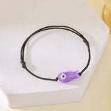 Gros plan sur le Bracelet Poisson Violet Ajustable, posé sur un support, montrant la brillance et la forme épurée du pendentif.
