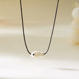 Gros plan sur le Collier Poisson Blanc Nacré sur Cordon Ajustable, illustrant le pendentif poisson au fini nacré.