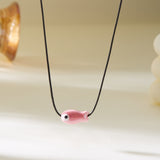 Gros plan sur le Collier Poisson Rose sur Cordon Ajustable, soulignant la teinte pastel du pendentif.