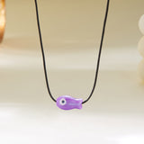 Gros plan sur le Collier Poisson Violet sur Cordon Ajustable, illustrant le pendentif poisson au style épuré