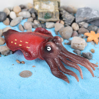 Figurine Calmar Rouge Tentacules placée dans un décor marin, soulignant sa texture réaliste et ses motifs colorés