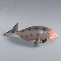 Figurine Dugong Gris en résine, avec des taches sombres sur le dos et une queue en forme de pagaie.
