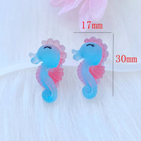 Deux figurines Hippocampe en résine bleu et rose, mesurant environ 30 mm x 17 mm, présentées sur fond blanc pour illustrer leurs dimensions.
