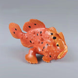 Figurine Poisson Baudroie Orange en résine, présentant une texture bosselée et des taches noires sur la peau.
