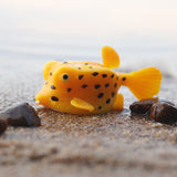 figurine poisson coffre jaune sur le sable