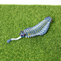 Figurine Poisson Fossile Bluish placée sur du gazon, mettant en évidence son aspect fossilisé et sa couleur bleutée.