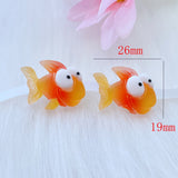 Deux figurines Poisson Rouge en Résine, mesurant environ 26 mm x 19 mm, présentées sur fond blanc pour illustrer leur taille.

