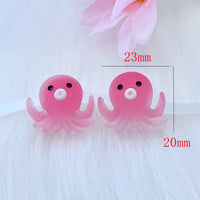 Deux figurines Poulpe en résine rose, mesurant environ 23 mm x 20 mm, présentées sur fond blanc pour illustrer leurs dimensions.
