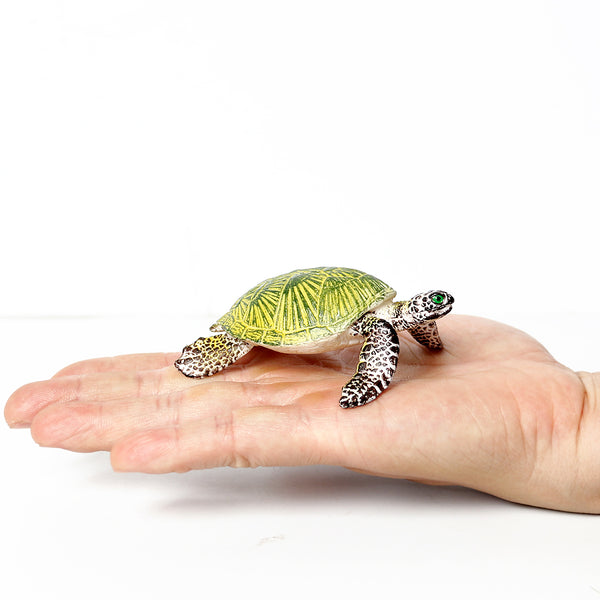 Figurine Tortue de Mer verte présentée dans la paume d’une main, mettant en avant sa taille compacte et ses motifs travaillés