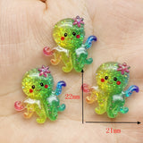 Lot de figurines Pieuvre Arc-en-Ciel en résine pailletée, décorées d'une petite fleur, mesurant environ 22 mm x 21 mm, présentées dans la main pour illustrer leur taille.
